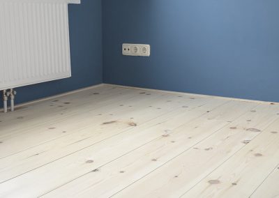 Grenen vloer met hard wax en een blauwe muur